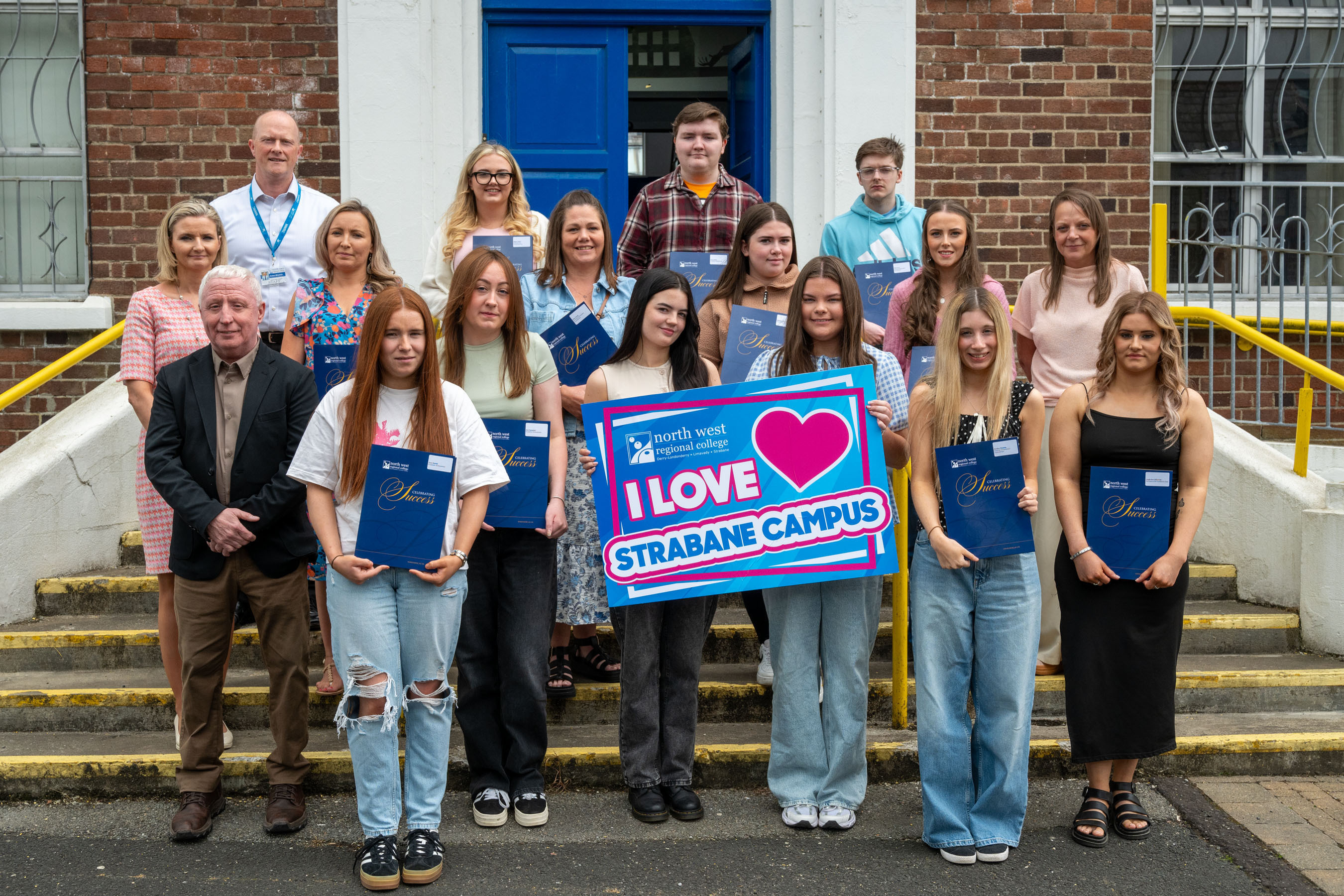 group of people outside a college campus holding a I Love Strabane Campus sign