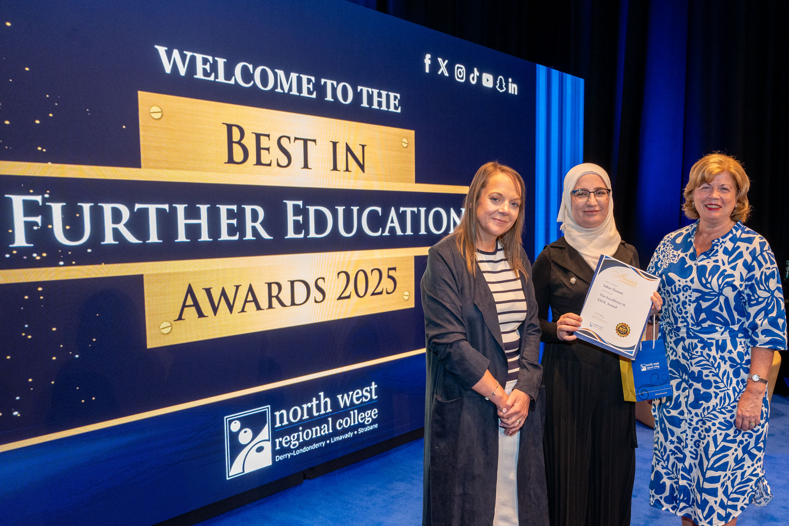 Three people at celebration event. One is holding a certificate. There is NWRC branding in the background