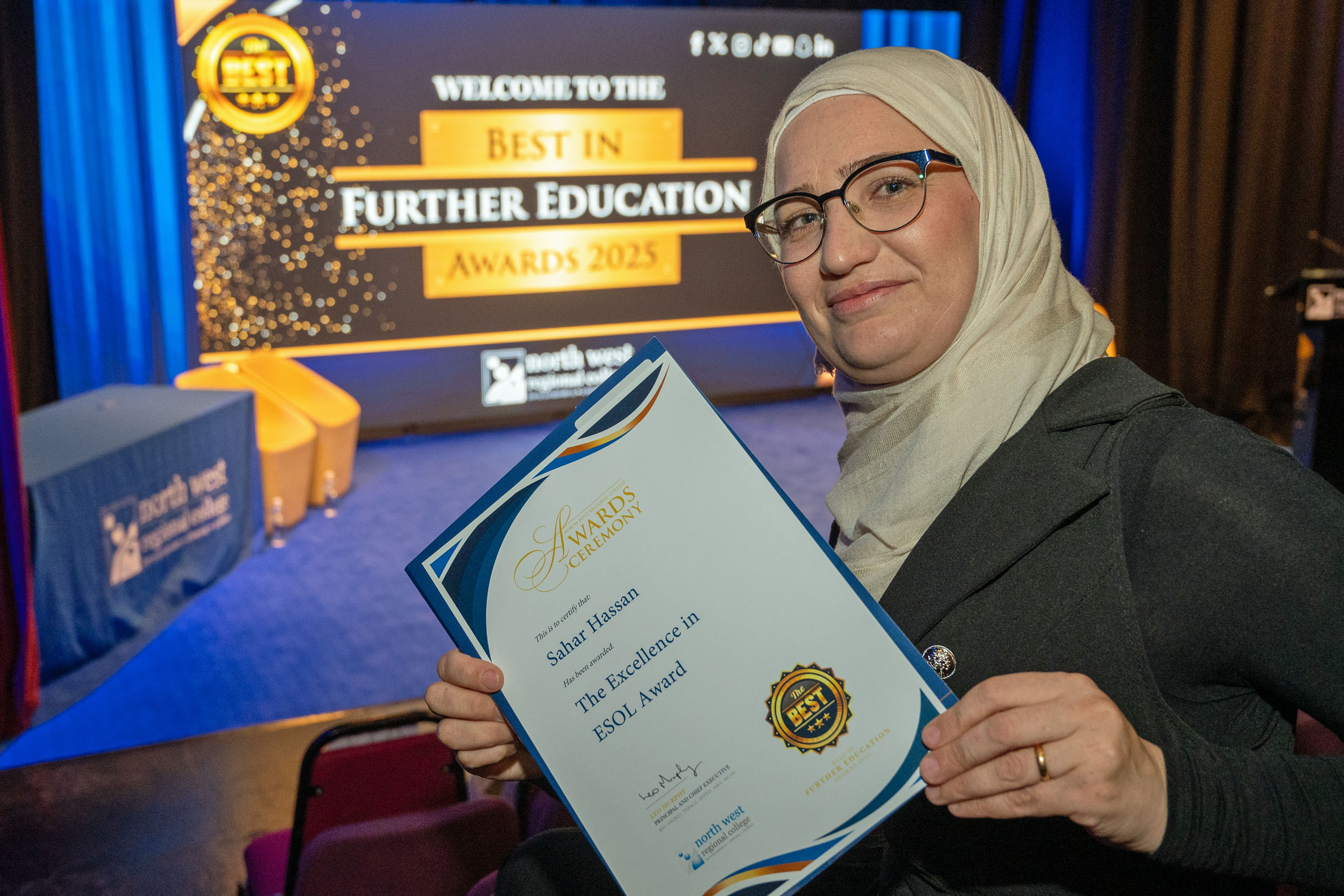 Woman in a theatre holding a certificate for Excellence in ESOL.