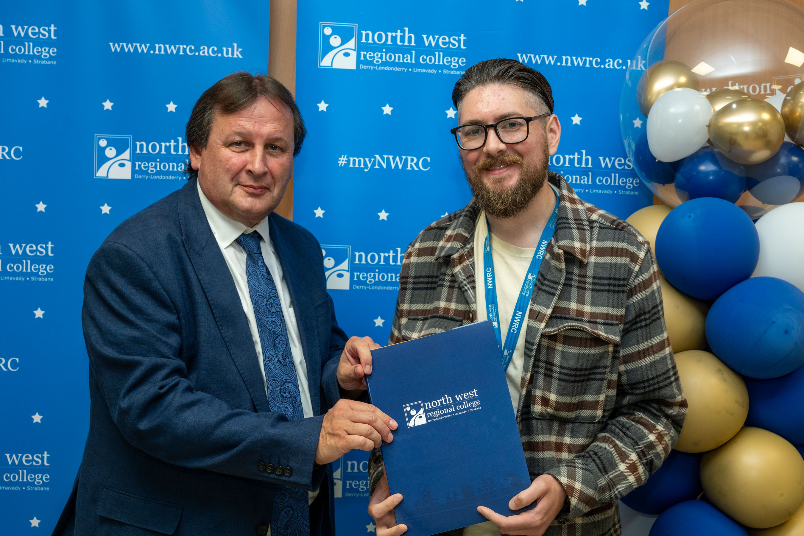 Two men in front of a NWRC blue screen holding a presentation holder.