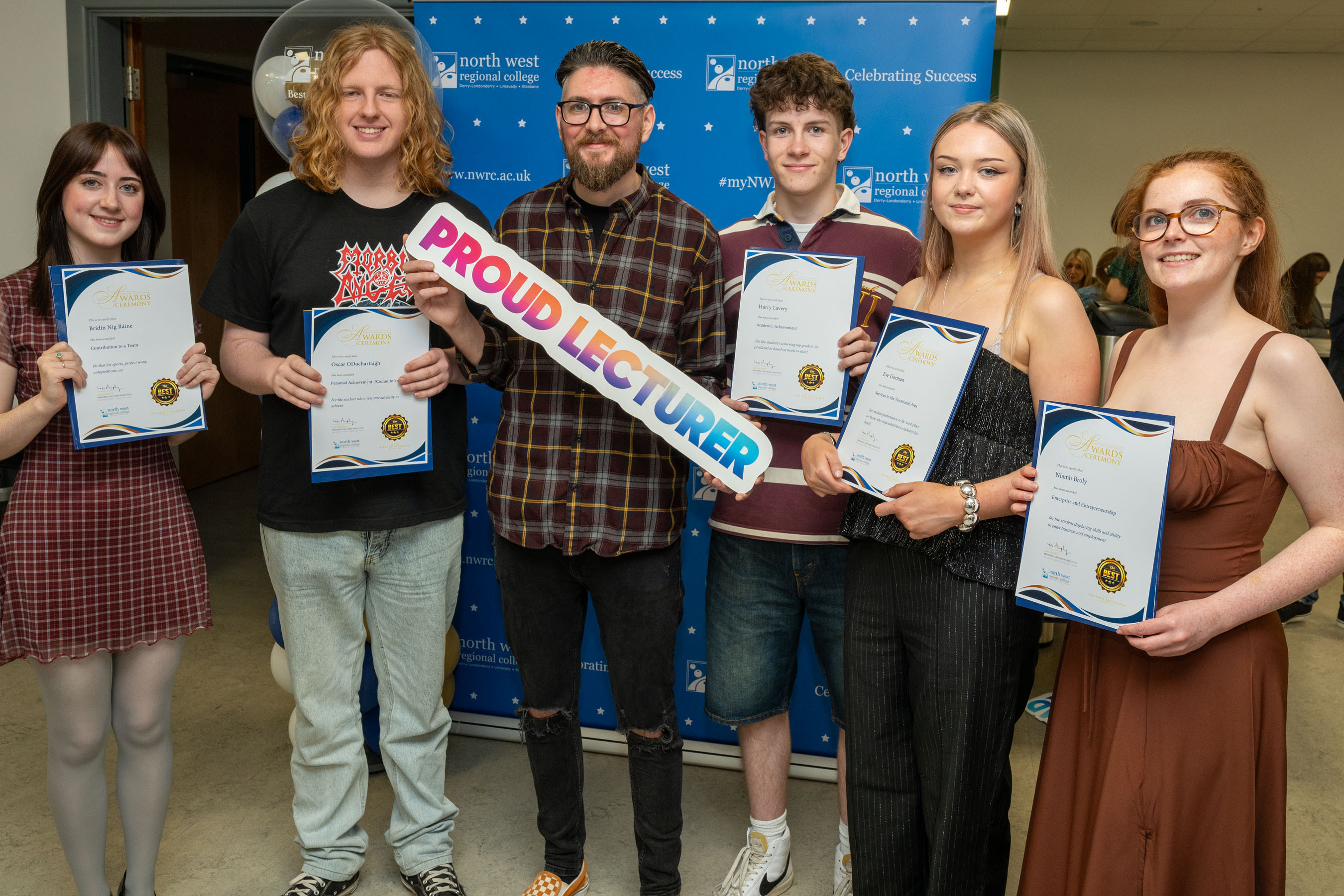 Five students and their lecturer. The lecturer is holding a proud lecturer sign