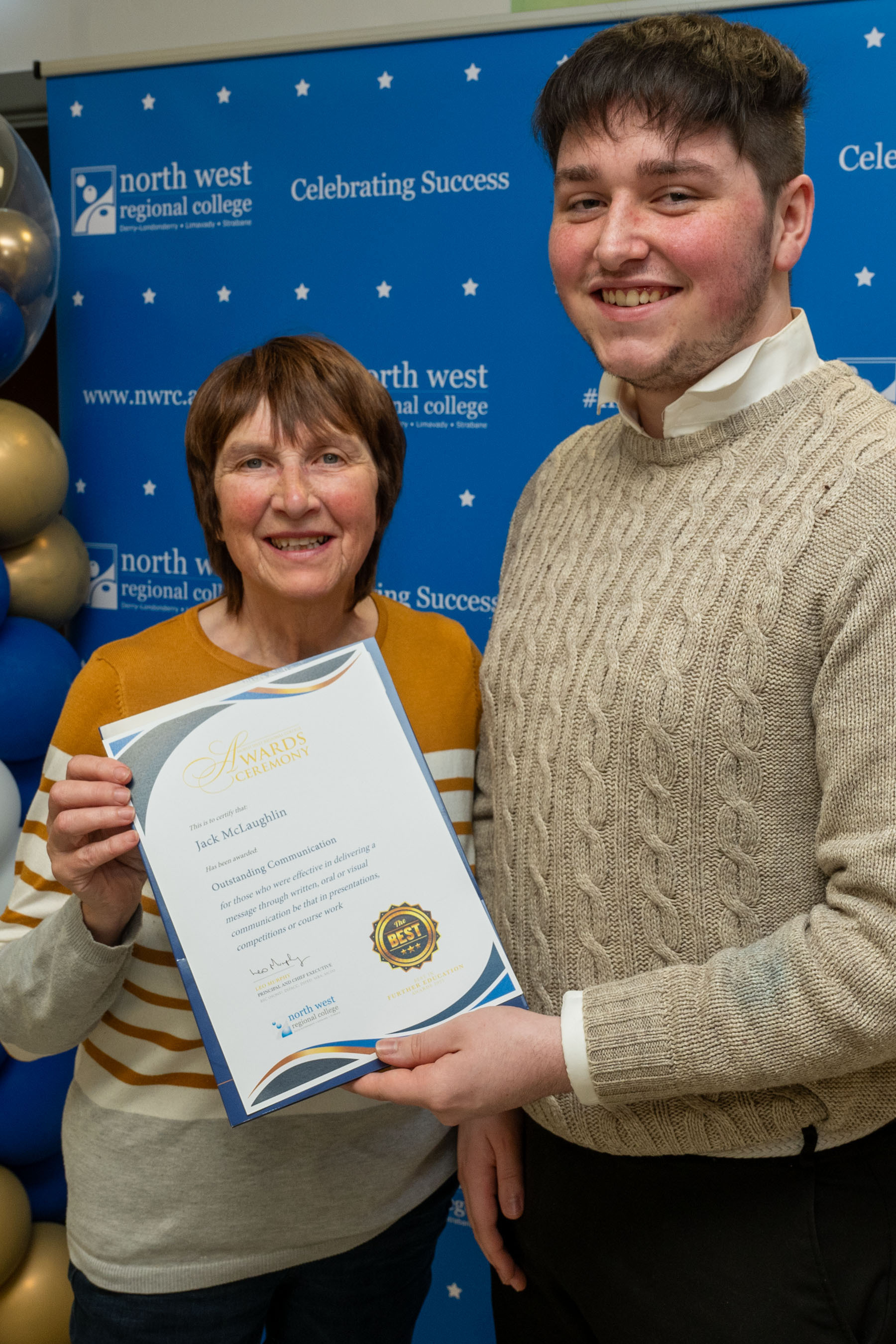 Two people at celebration event. They are holding a certificate for outstanding achievement