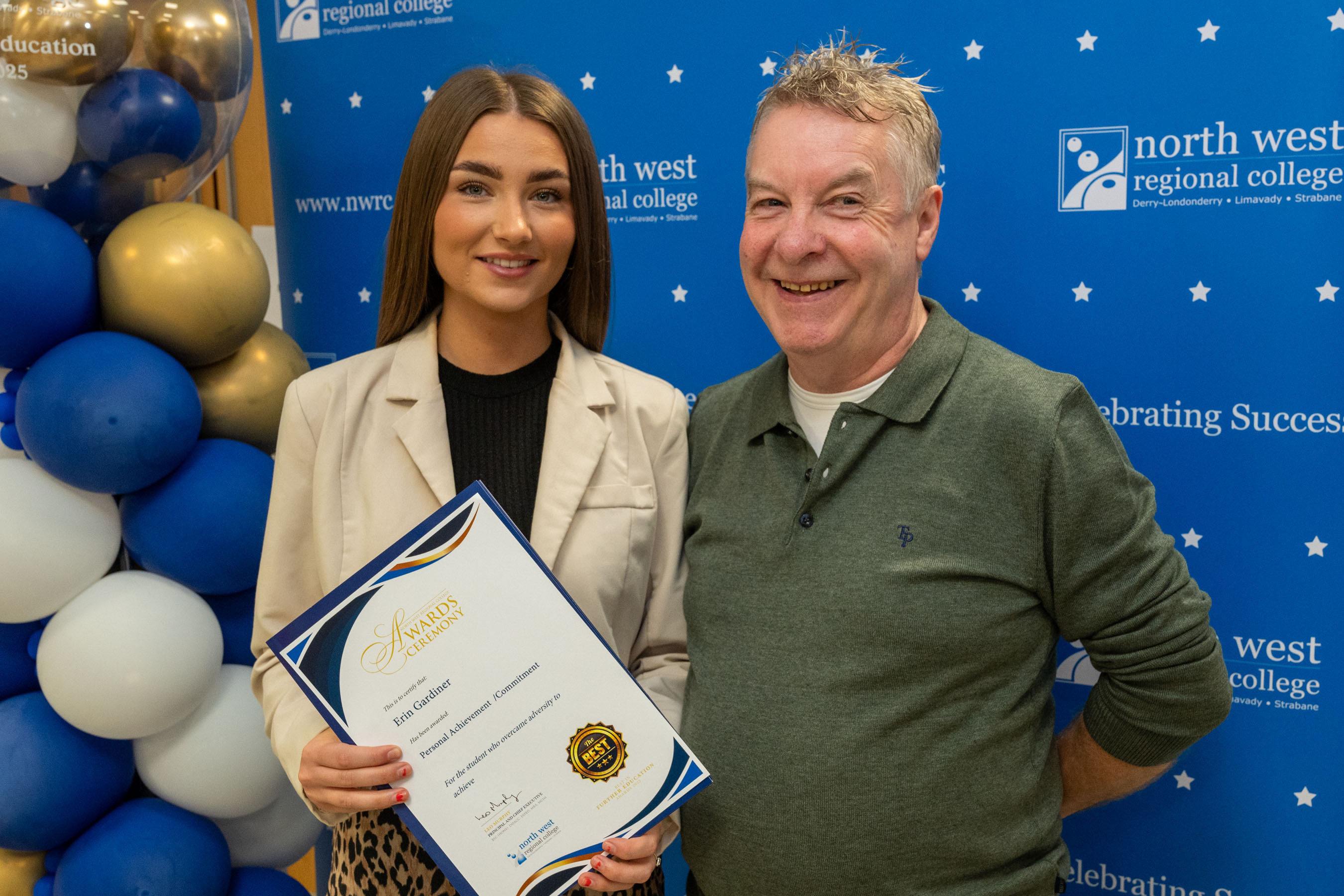 Two people at celebration event. One is holding a certificate