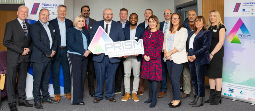 group of business men and women holding a photo prop that reads 'PRISM'