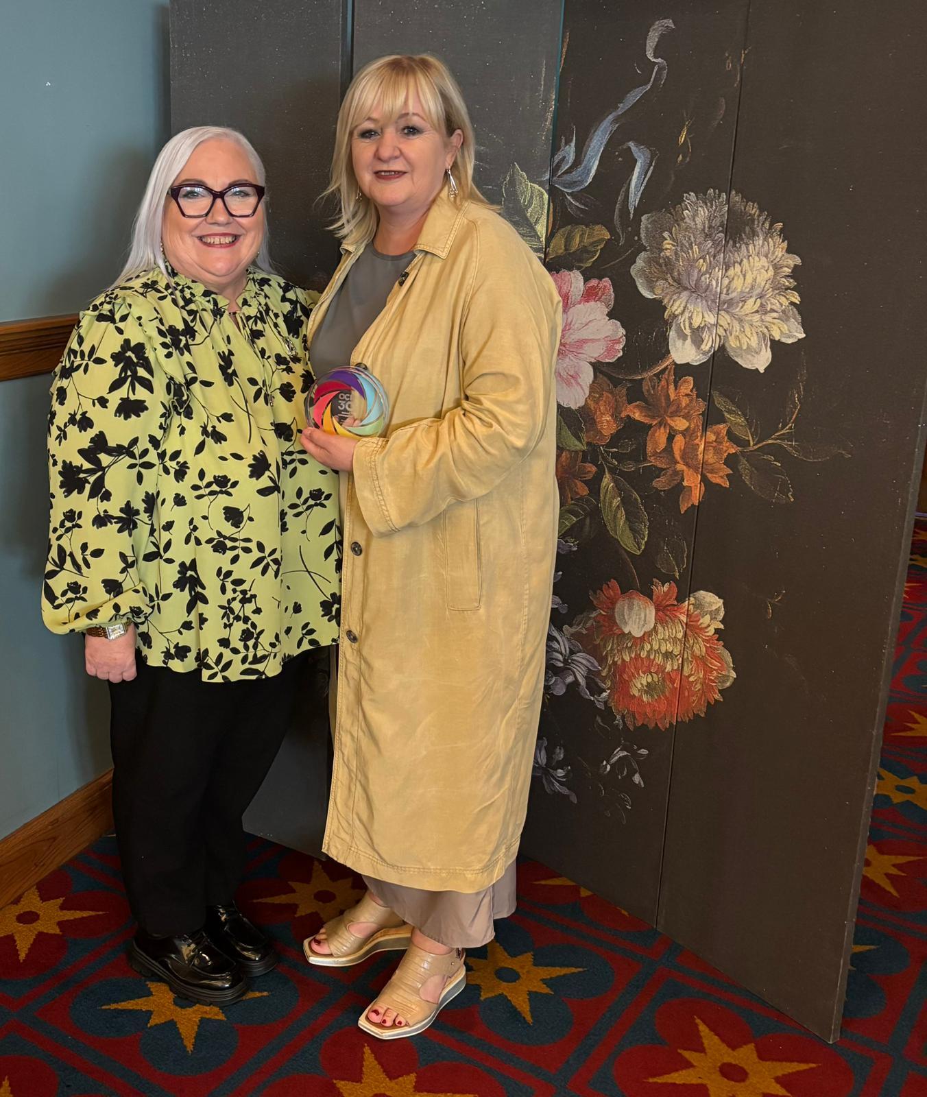 two women at awards ceremony holding an award
