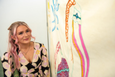 Young female student looks at her art on the wall