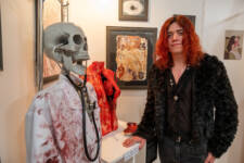 Student standing beside work at art exhibition