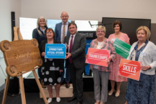 Group of people stand beside wooden 'Springtown Campus' sign