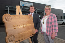 man and woman stands beside wooden 'Springtown' campus sign