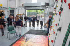 Group of people stand beside a climbing wall