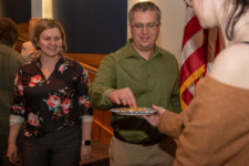 Two people take crisps from a plate being offered by another person