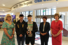 Group of five people with young male student in centre holding an award