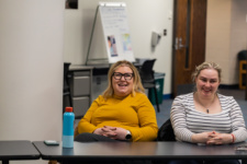 Two people sitting behind desks smiling at the camera