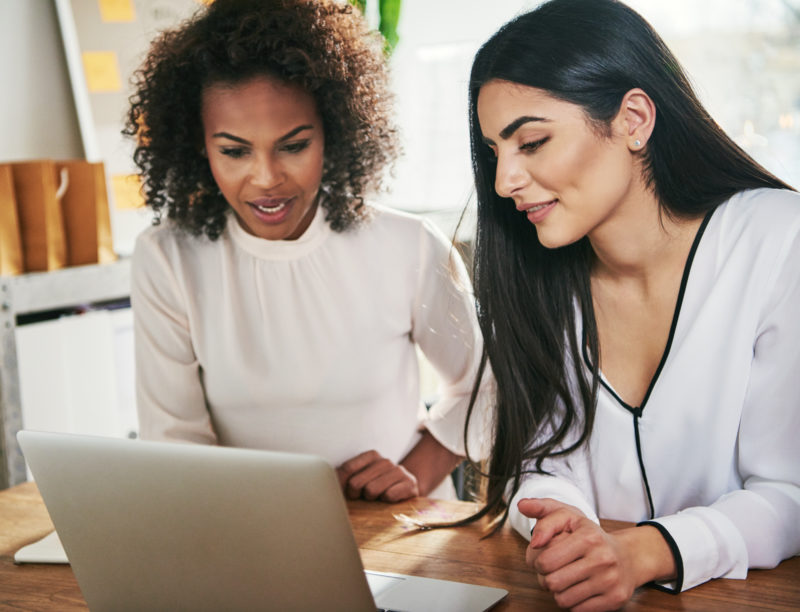 Two business women working on a laptop
