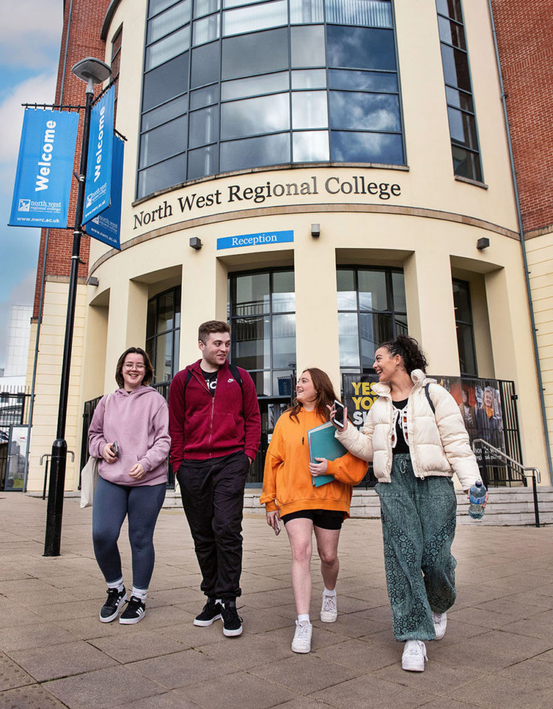 3 female students and 1 male student walking out of Strand Road campus laughing together