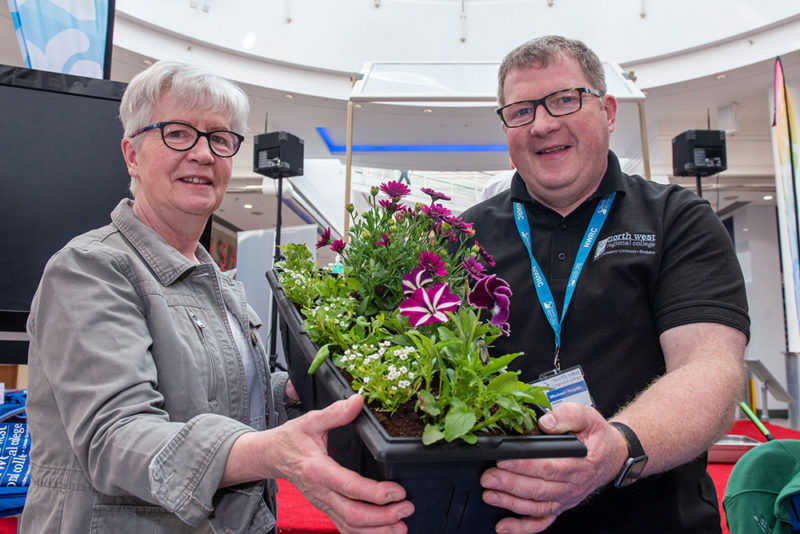 Male member of staff demonstrates a flower pot with a female