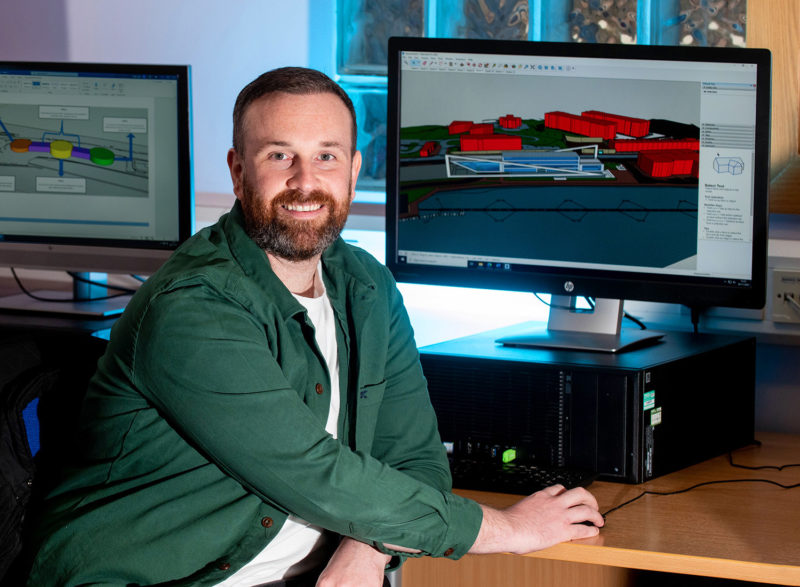 Mature male construction student smiles at camera while working on PC