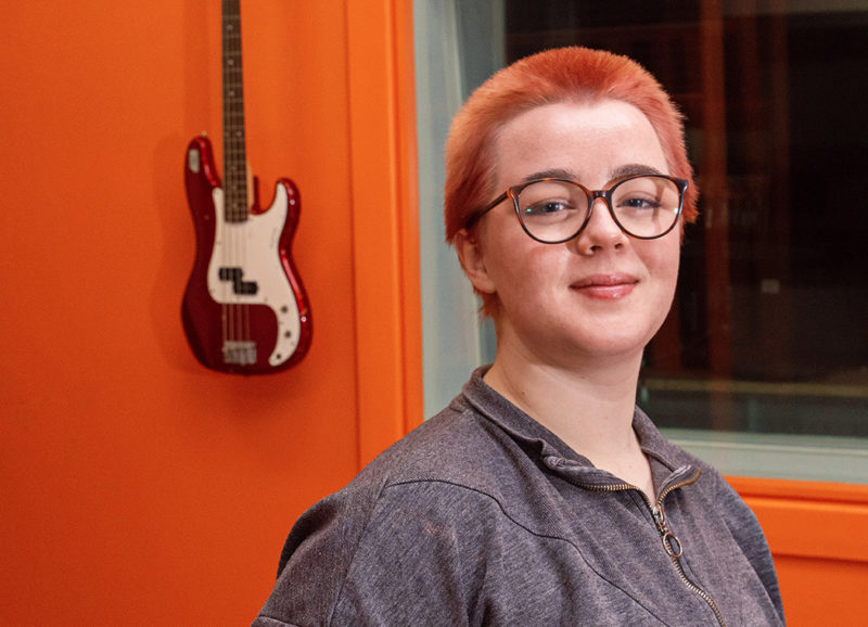 Sarah Jane Campbell music student in recording studio with guitar on the wall