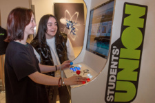 Two female students play games on the Students Union arcade machine