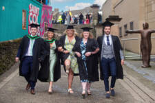 Group of male and female graduates walking arm in arm along the Derry City Walls