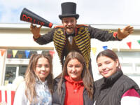 Three young girls in front of circus performer on stilts