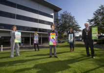 People standing outside holding signs with a building behind