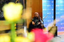 Male cello player performs at NWRC Graduation Ceremony with flowers in foreground