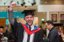 Male graduate raises his arm in victory and celebration