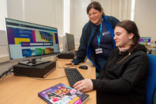 member of staff helps female student apply for a course using a computer