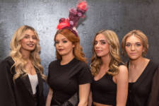 hairdressing student stands with three female models in front of grey backdrop