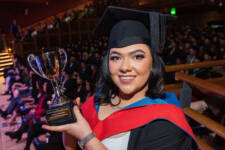 Female graduate smiling holding her trophy at Graduation Ceremony