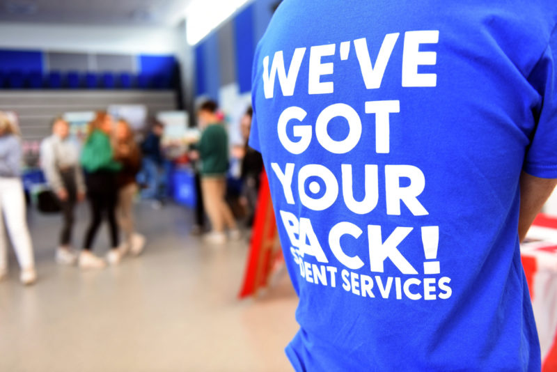 College staff wearing t-shirt with "We've got your back" written on the back