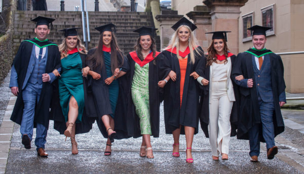 Graduates walk together arm-in-arm along the Derry Walls