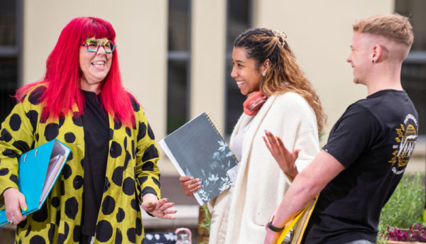 Group of 3 students male and female laughing together on campus