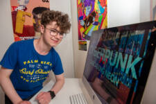 young male presenting his digital artwork on apple mac at Art Exhibition