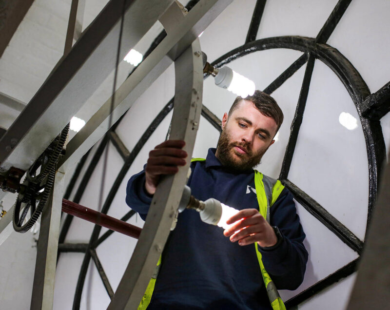 male electrical engineer fitting bulbs on tower clock
