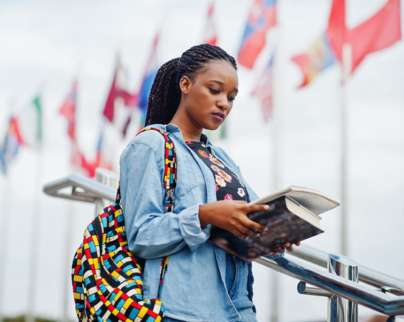 African student female posed with backpack and school items on campus