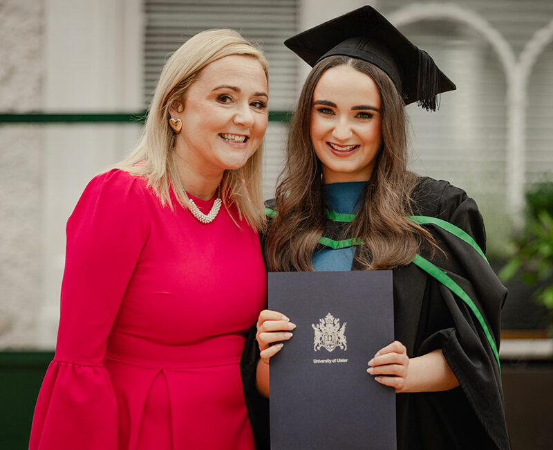 Female graduate holding certificate with her mother in a red dress