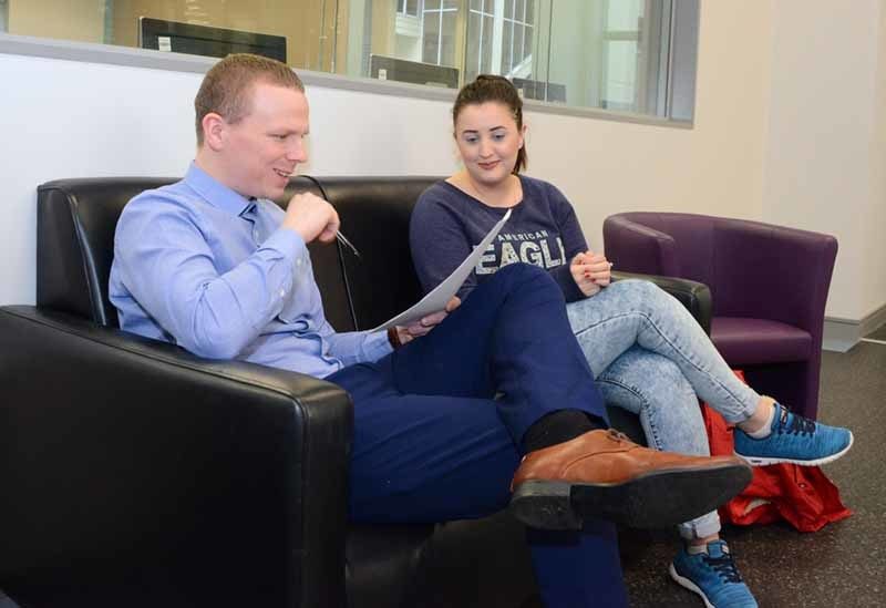 NWRC staff member and student sitting on sofa chatting and looking at a document