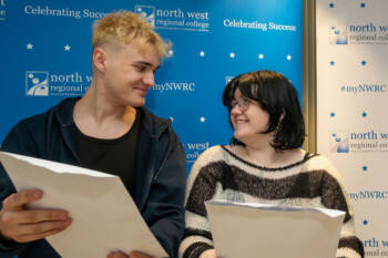Two students standing in front of NWRC branding holding envelopes.