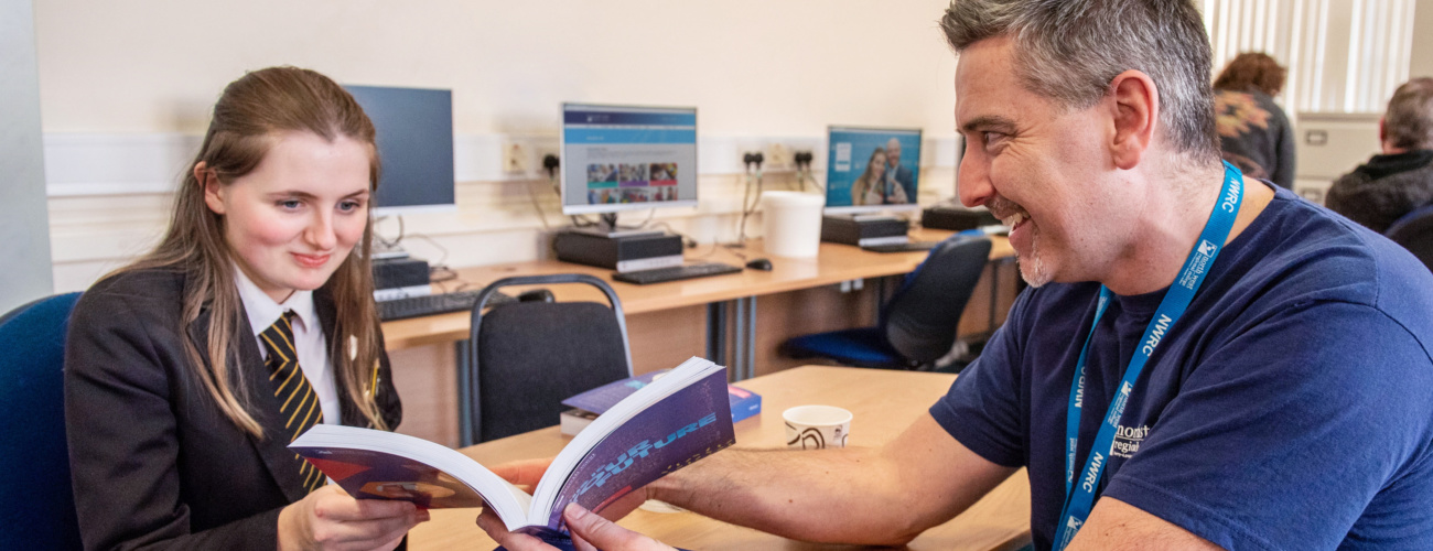 Careers Advisor giving school student advice while looking through course prospectus