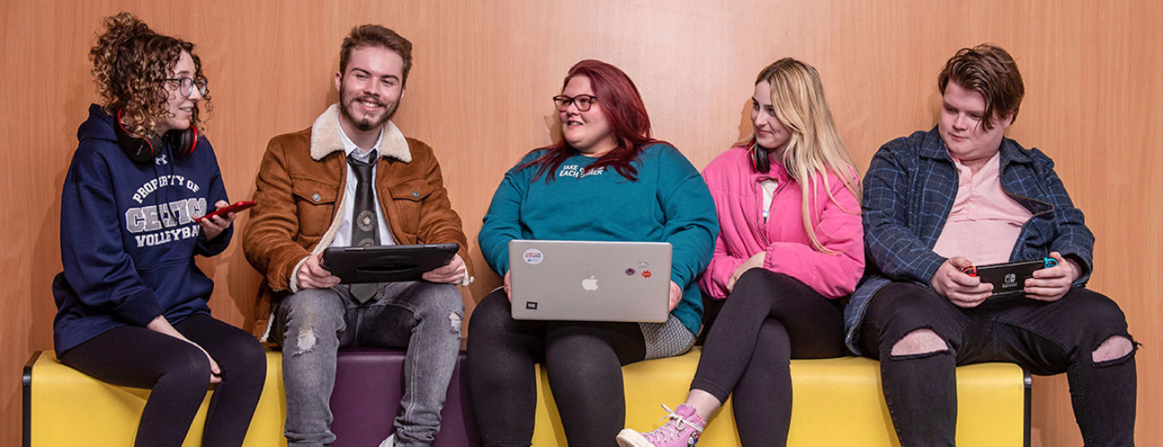 Group of relaxed students casually sitting on bench