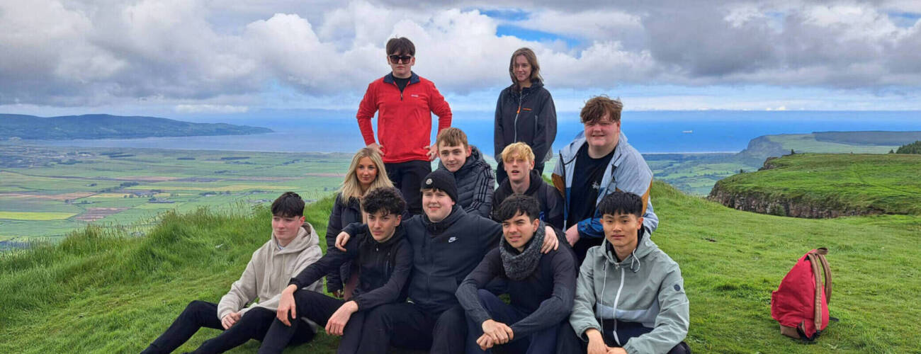 group of young people sitting at the top of a mountain