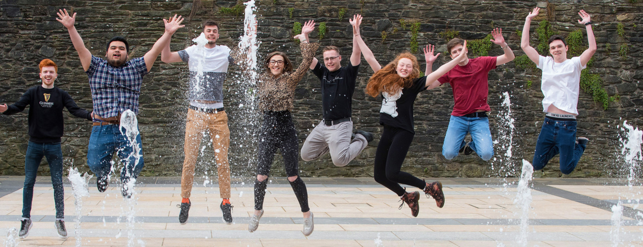 Students jumping in front of fountain
