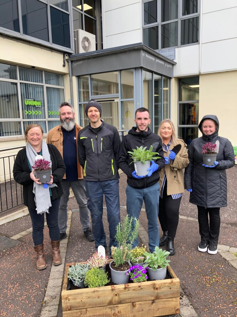 students and staff pictured holding plants