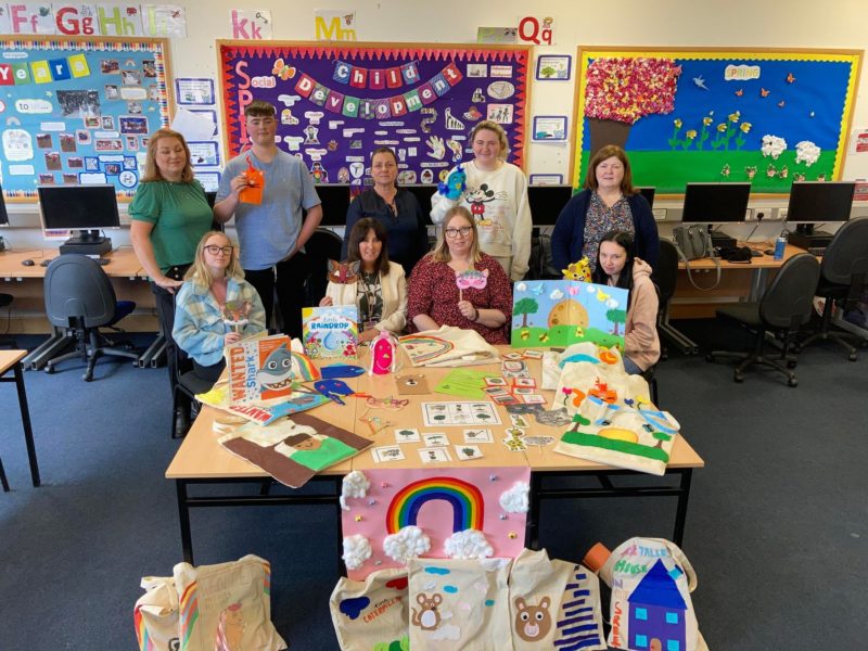 Group of nine people in a classroom setting with children's books and the story sacks