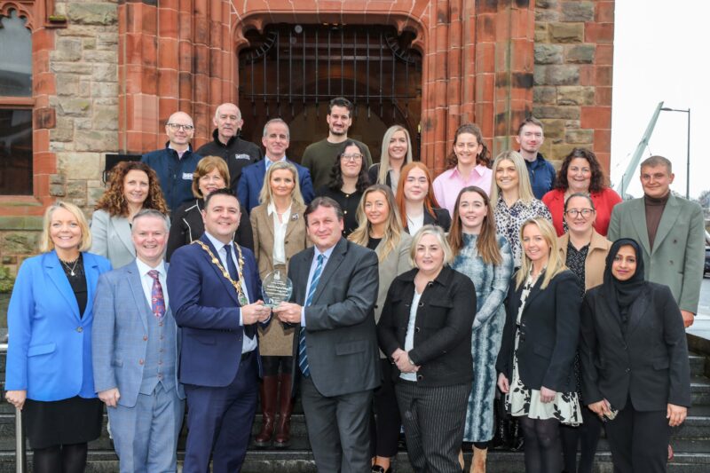 group pictured outside Derry's Guildhall steps. The Mayor is at the front presenting an award to a gentleman