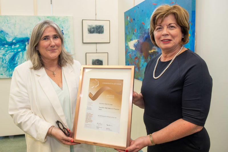 Two members of staff pictured holding the bronze award