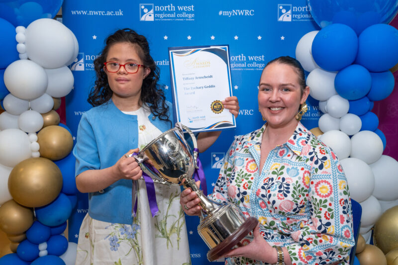 two ladies in front of NWRC branding holding a certificate and tropy