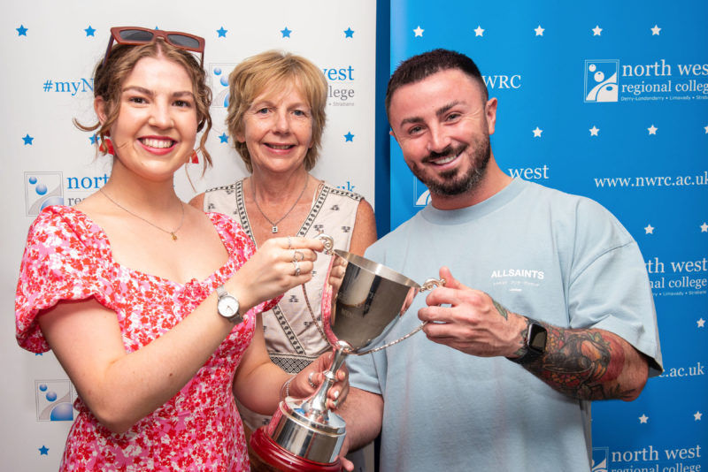 Three people pictured holding the award